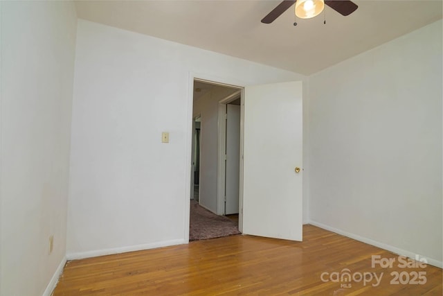 empty room featuring baseboards, a ceiling fan, and wood finished floors