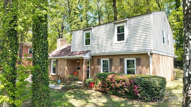 view of front of home featuring brick siding and a chimney