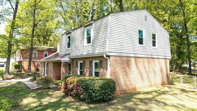 view of front facade featuring brick siding, a front lawn, fence, and a gate