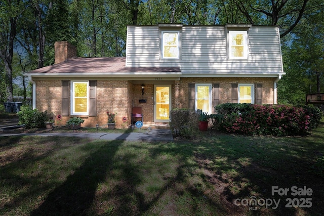 view of property featuring a front yard, brick siding, and a chimney