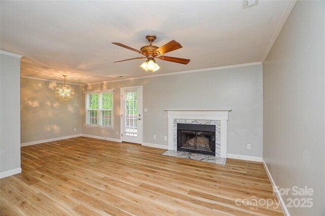 10805 Winterbourne Ct, Charlotte, NC 28277 - unfurnished living room featuring baseboards, light wood-type flooring, crown molding, ceiling fan with notable chandelier, and a premium fireplace