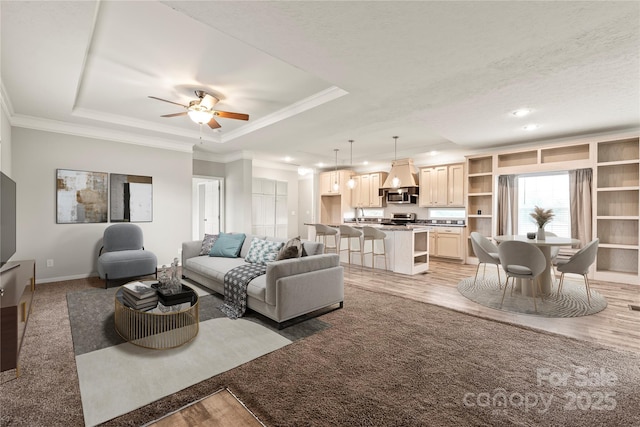 living area with crown molding, a tray ceiling, recessed lighting, ceiling fan, and baseboards