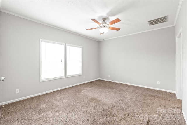 carpeted empty room with ceiling fan, ornamental molding, baseboards, and visible vents
