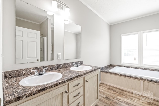 full bath featuring a sink, ornamental molding, a bath, and wood finished floors