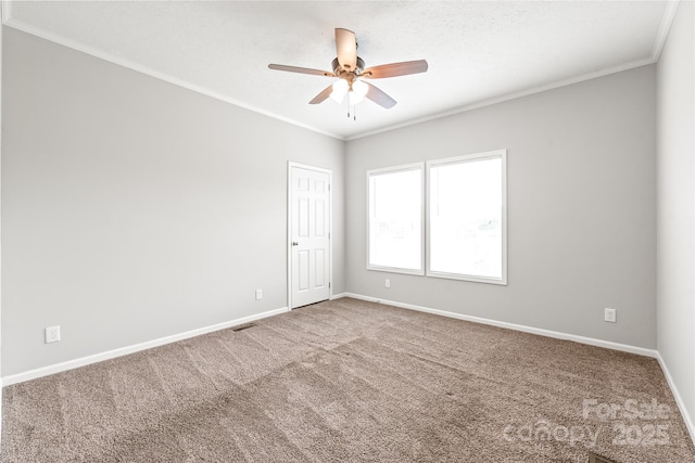 carpeted empty room with crown molding, visible vents, baseboards, and ceiling fan