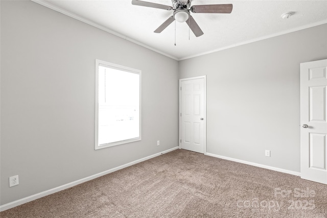 carpeted empty room with ceiling fan, baseboards, and ornamental molding