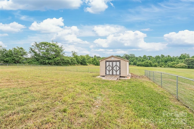 view of yard with a fenced backyard, a rural view, an outdoor structure, and a storage shed