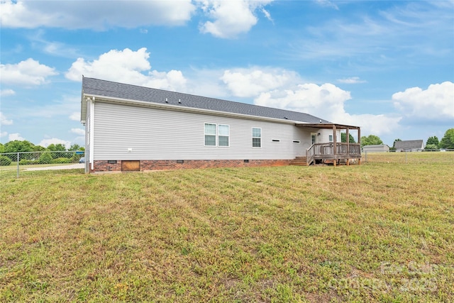 rear view of house with a lawn, a wooden deck, fence, and crawl space