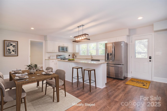 6008 Corkstone Dr, Mint Hill, NC 28227 - kitchen with appliances with stainless steel finishes, a center island, white cabinets, decorative backsplash, and dark wood-type flooring