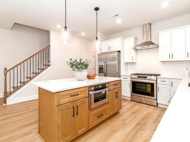 kitchen with stainless steel appliances, wall chimney exhaust hood, light wood-style floors, backsplash, and light countertops