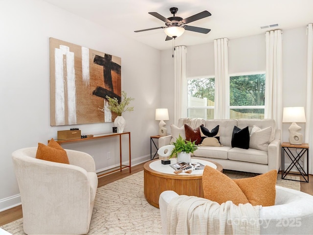 living area featuring wood finished floors, ceiling fan, and baseboards