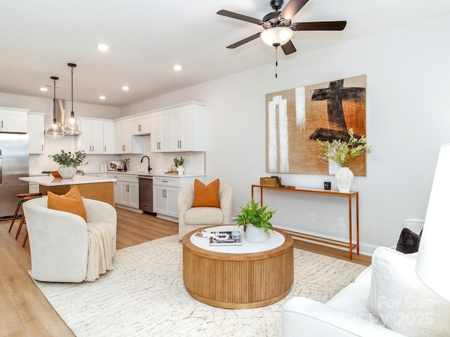 living area with light wood-style floors, ceiling fan, and recessed lighting