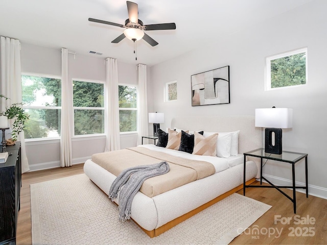 bedroom with wood finished floors, multiple windows, and baseboards