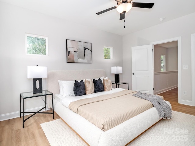 bedroom featuring light wood-style flooring, baseboards, and a ceiling fan