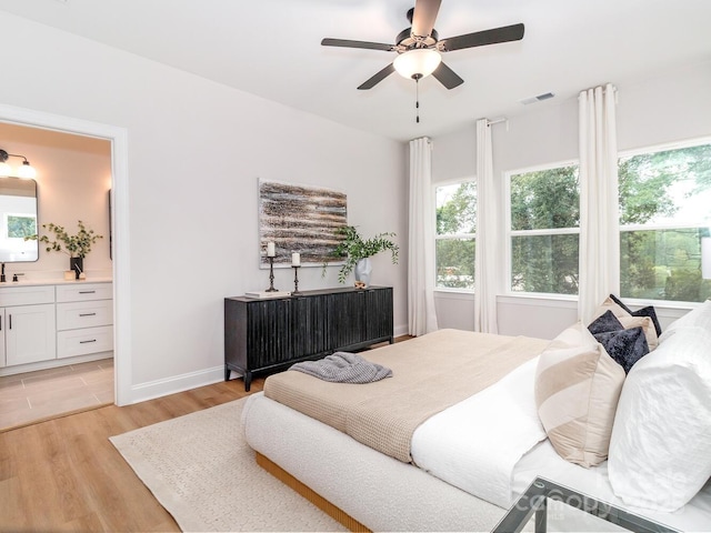 bedroom featuring multiple windows, light wood-style floors, and ensuite bathroom