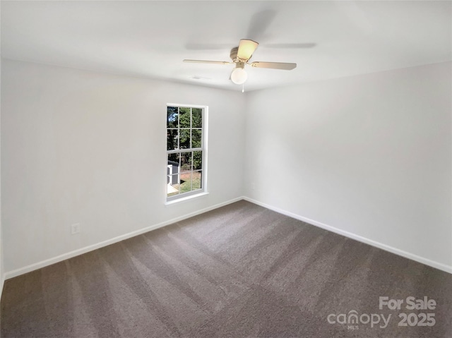 empty room with baseboards, dark carpet, and ceiling fan
