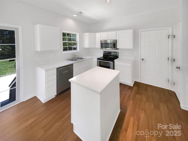 kitchen featuring stainless steel appliances, white cabinets, a sink, and wood finished floors
