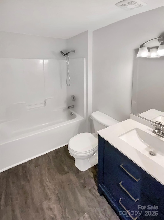 full bath featuring visible vents, toilet, tub / shower combination, vanity, and wood finished floors