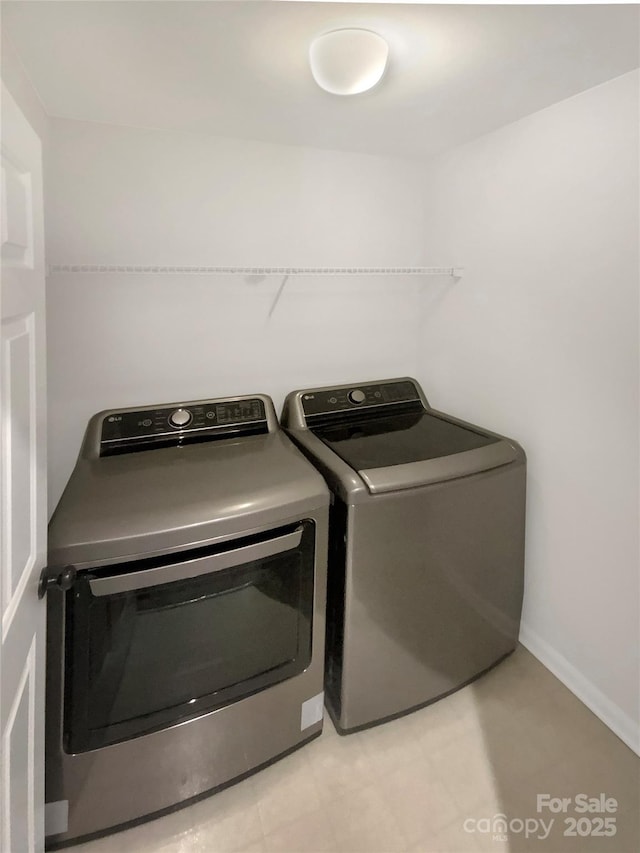 laundry room with light tile patterned floors, washing machine and dryer, laundry area, and baseboards