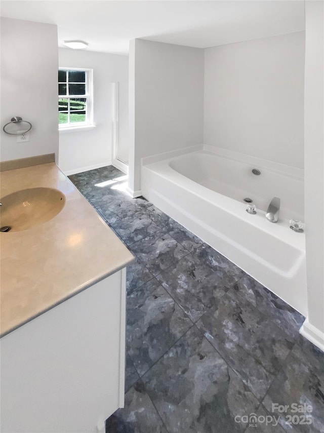full bathroom featuring vanity, baseboards, and a garden tub