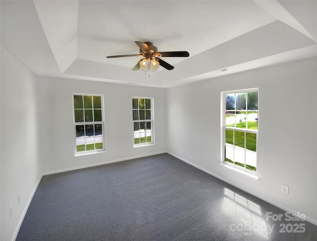 unfurnished room featuring a tray ceiling, baseboards, and ceiling fan