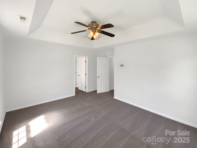 empty room with visible vents, ceiling fan, a raised ceiling, and baseboards