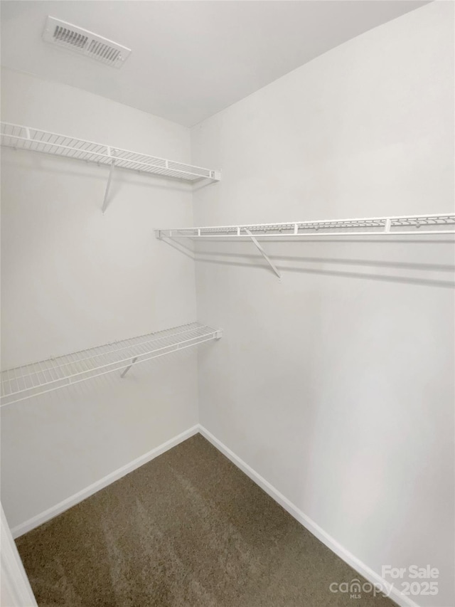 walk in closet featuring dark carpet and visible vents