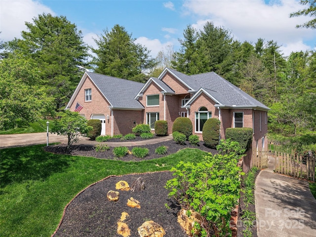 view of front of home with brick siding, fence, a shingled roof, a garage, and a front yard