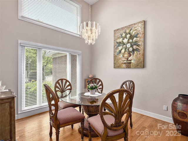 dining room with light wood-style flooring, a chandelier, and baseboards