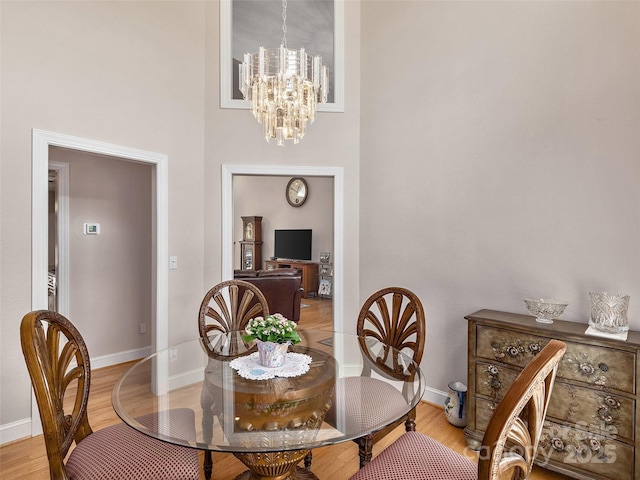 dining area with light wood-style floors, a notable chandelier, and baseboards