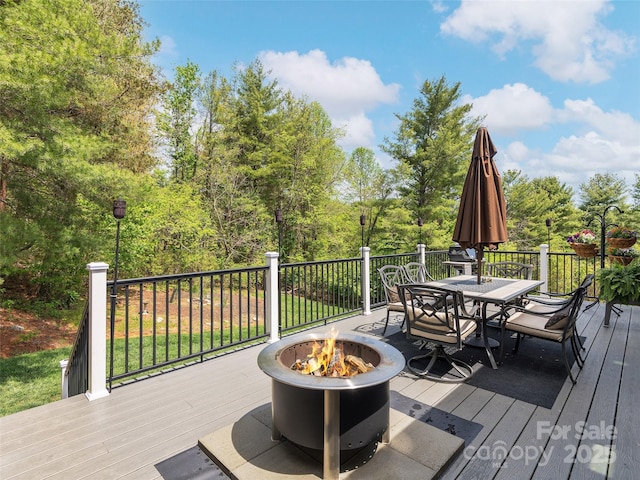 wooden terrace featuring outdoor dining space and an outdoor fire pit
