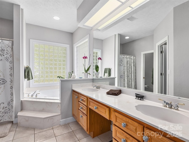 bathroom with double vanity, tile patterned floors, a bath, and a sink
