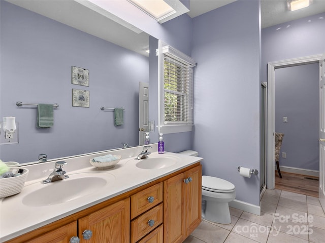 bathroom with double vanity, toilet, tile patterned flooring, and a sink
