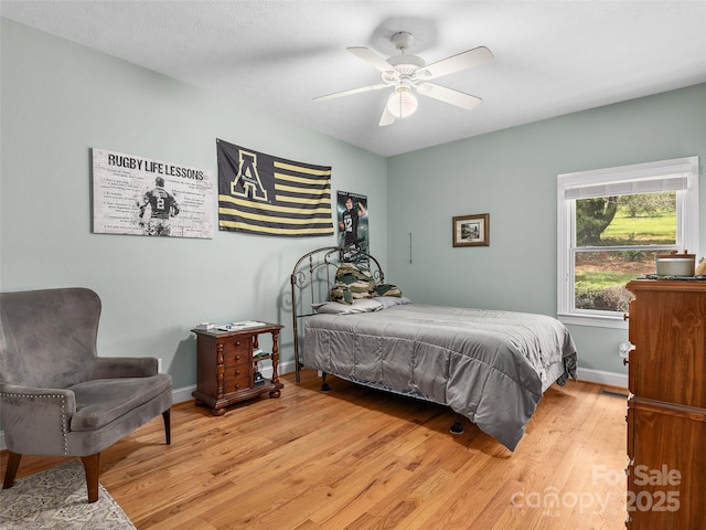 bedroom featuring baseboards, a ceiling fan, and light wood-style flooring