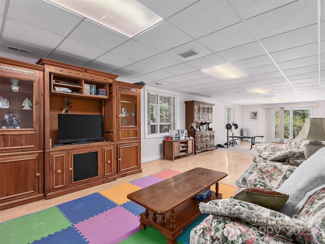 living area featuring a paneled ceiling, visible vents, and light wood-type flooring