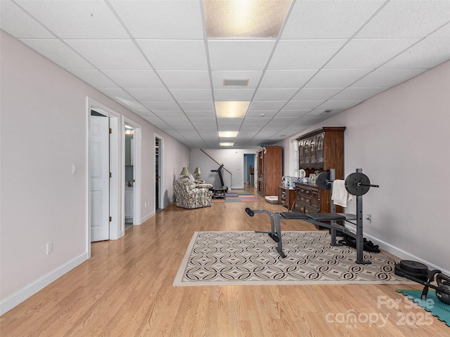 workout area featuring baseboards, wood finished floors, and a drop ceiling