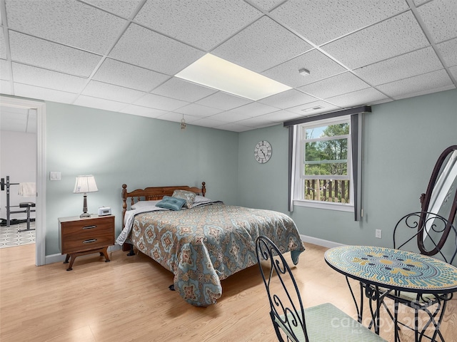 bedroom featuring a paneled ceiling, wood finished floors, and baseboards