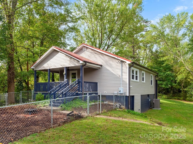 bungalow-style home with a porch, an attached garage, fence, central air condition unit, and a front lawn