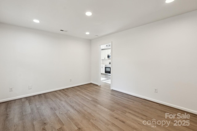 unfurnished room featuring baseboards, wood finished floors, and recessed lighting