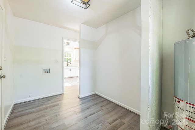 interior space with baseboards, wood finished floors, a sink, and gas water heater