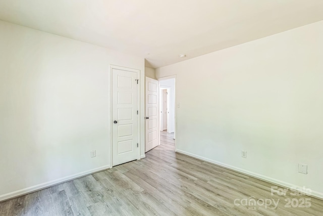 spare room featuring baseboards and wood finished floors