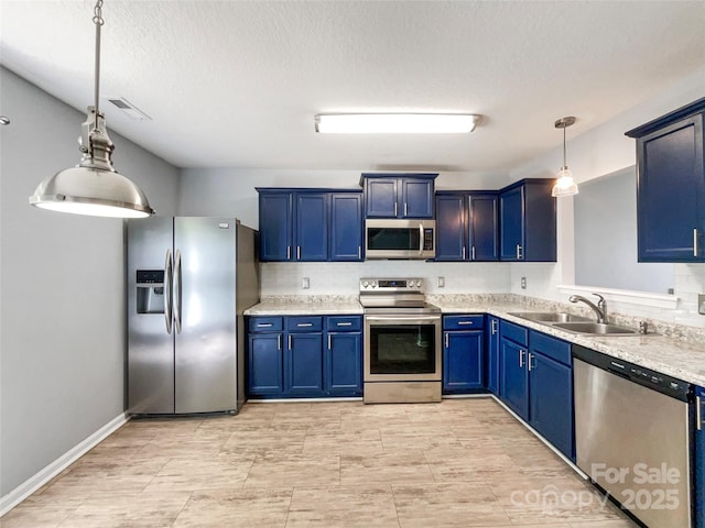 kitchen with blue cabinetry, light countertops, a sink, stainless steel appliances, and decorative light fixtures