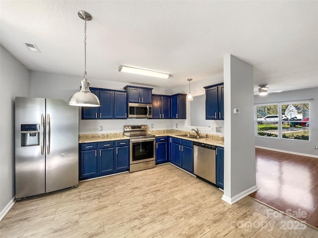 kitchen featuring blue cabinets, visible vents, stainless steel appliances, a sink, and hanging light fixtures