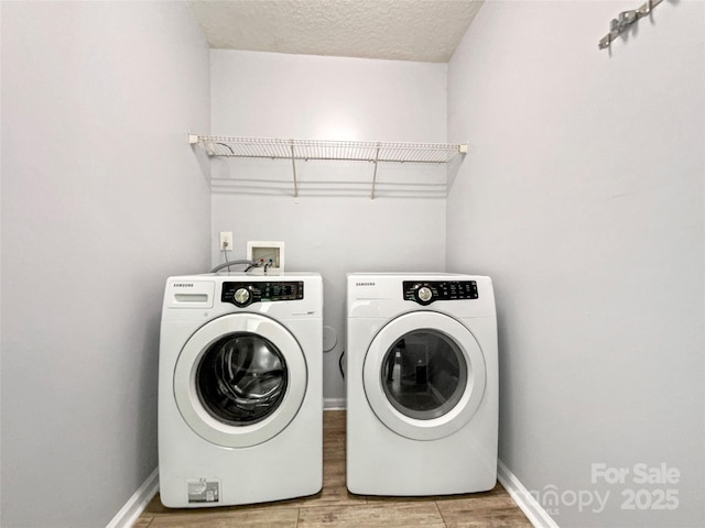 clothes washing area featuring washer and clothes dryer, wood finished floors, laundry area, and a textured ceiling