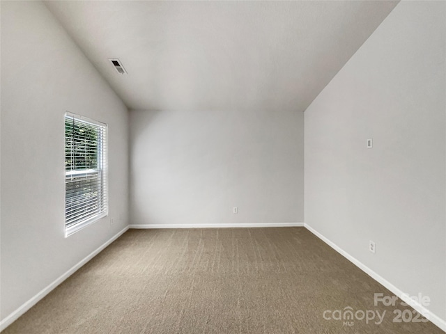 carpeted empty room featuring visible vents, baseboards, and vaulted ceiling