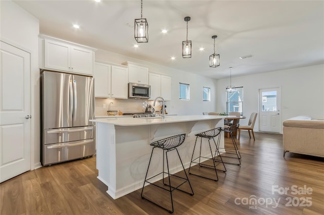 14224 Canemeadow Dr, Charlotte, NC 28278 - kitchen featuring appliances with stainless steel finishes, recessed lighting, dark wood finished floors, a breakfast bar, and a center island with sink