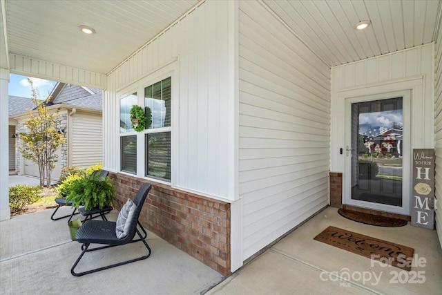 view of exterior entry featuring brick siding and covered porch