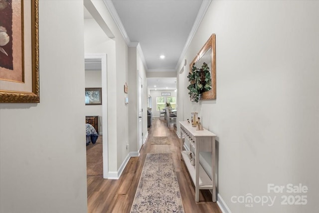 hallway with wood finished floors, baseboards, and ornamental molding