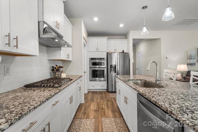 kitchen with white cabinets, under cabinet range hood, visible vents, a sink, and appliances with stainless steel finishes