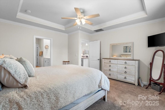 carpeted bedroom with a ceiling fan, ensuite bathroom, a tray ceiling, ornamental molding, and visible vents